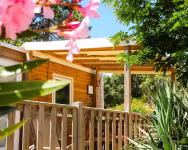 Terrasse en bois d'un chalet, entre lauriers-roses et palmiers
