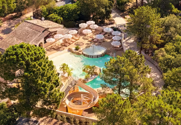 Vue aérienne du parc aquatique entouré de pins, avec ses parasols et son toboggan