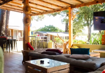Salon extérieur couvert, canapés et coussins colorés, ouvert sur les chalets