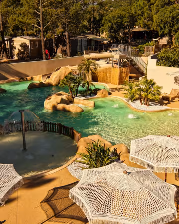 Piscine bordée de rochers et de parasols en macramé