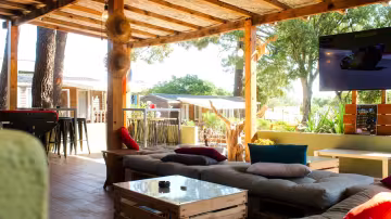 Salon extérieur couvert, canapés et coussins colorés, ouvert sur les chalets